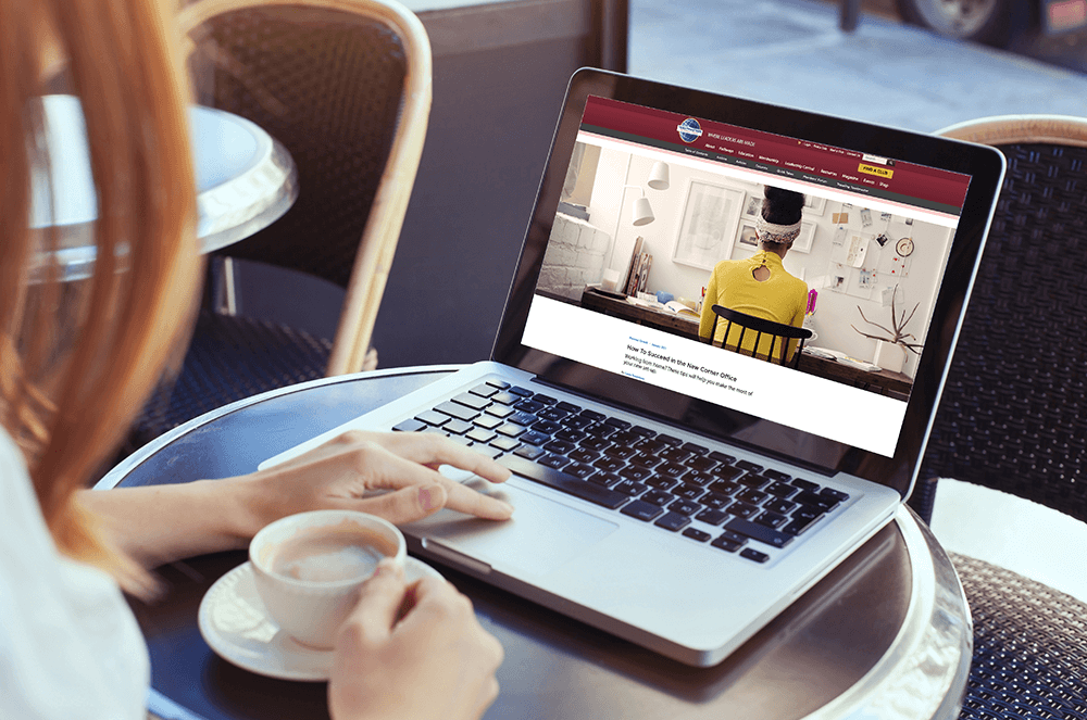 Woman holding coffee while reading on laptop